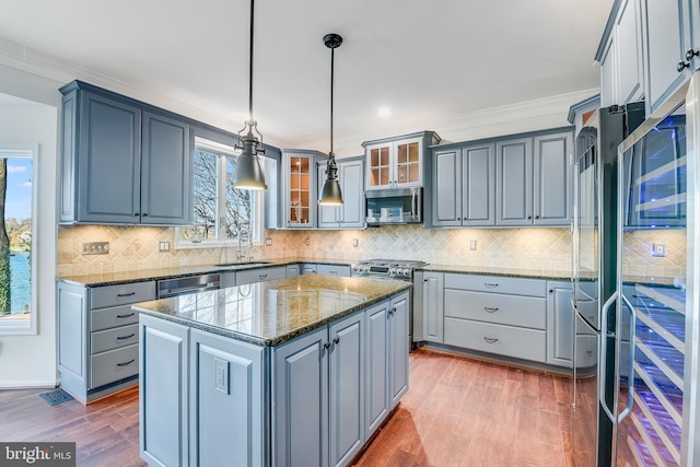 kitchen featuring decorative light fixtures, a kitchen island, a healthy amount of sunlight, and appliances with stainless steel finishes