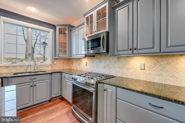 kitchen featuring gray cabinetry, hardwood / wood-style floors, dark stone counters, sink, and stainless steel appliances