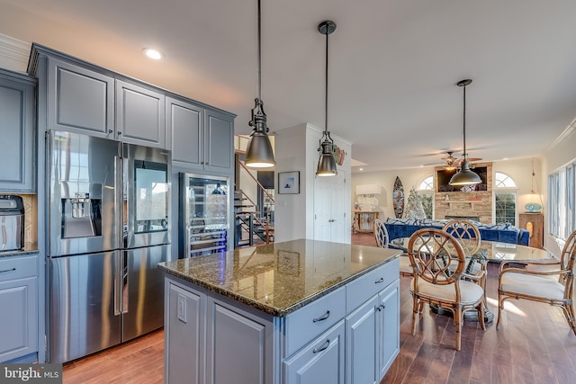 kitchen featuring stainless steel refrigerator with ice dispenser, a center island, dark stone counters, and wood-type flooring