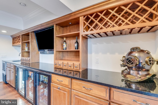 kitchen featuring sink, wine cooler, light hardwood / wood-style flooring, dark stone countertops, and ornamental molding