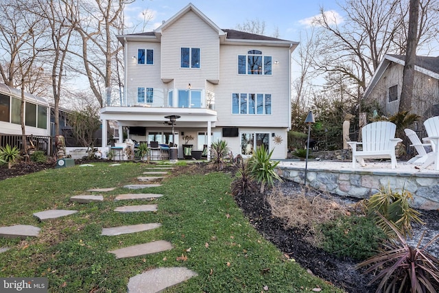 back of house with ceiling fan and a lawn