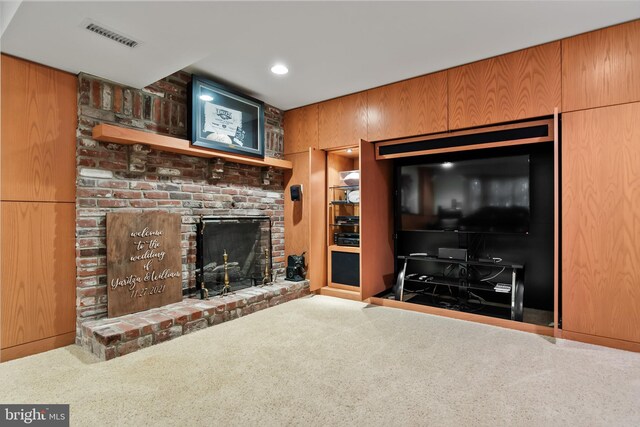 unfurnished living room with wood walls, carpet, and a brick fireplace