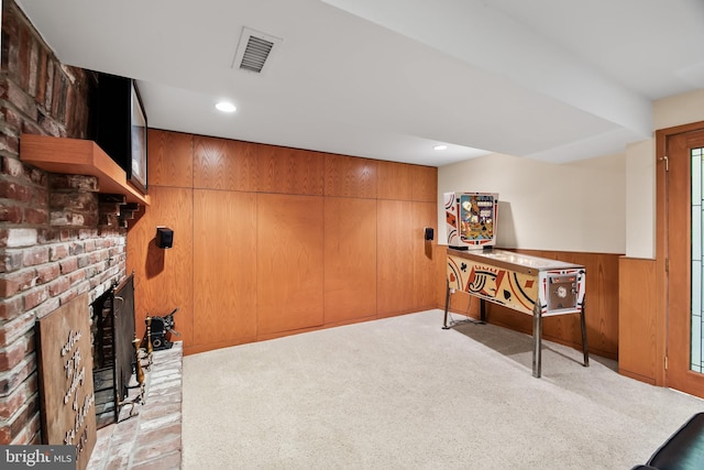 sitting room with wooden walls, light colored carpet, and a brick fireplace