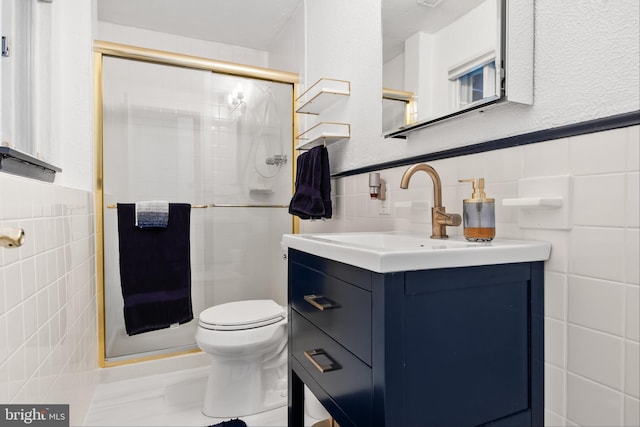 bathroom with vanity, toilet, an enclosed shower, and tile walls