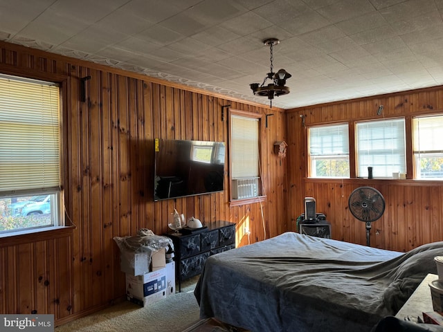 carpeted bedroom featuring wood walls and multiple windows