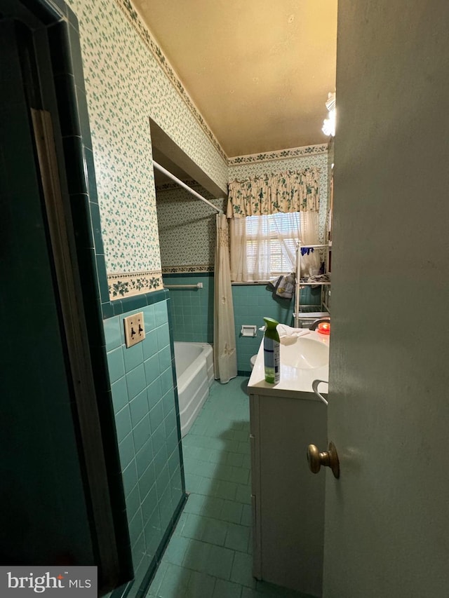 bathroom with vanity, shower / tub combo with curtain, and tile walls