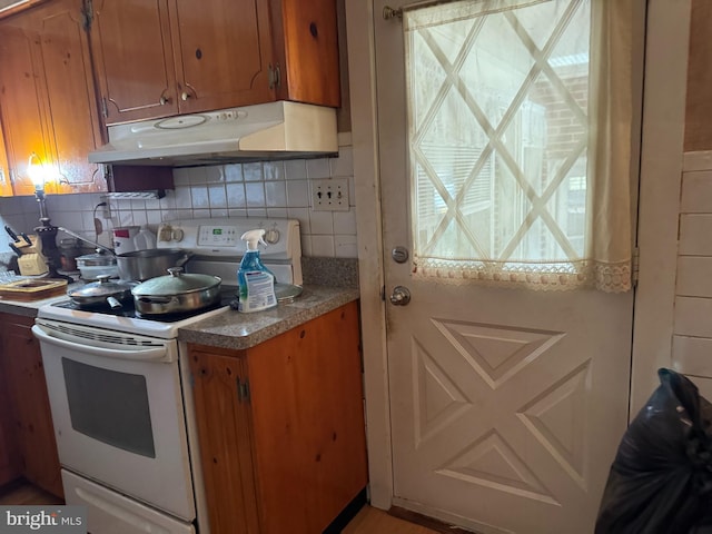 14423 Long Branch Rd, Woodford, VA 22580 - kitchen featuring white electric stove, under cabinet range hood, brown cabinetry, and backsplash