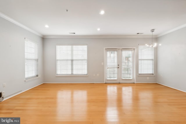 empty room featuring light wood-type flooring, crown molding, and a notable chandelier