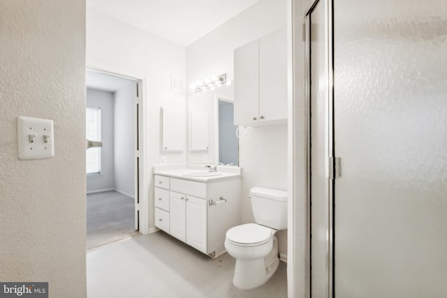 bathroom featuring vanity, toilet, and a shower with shower door