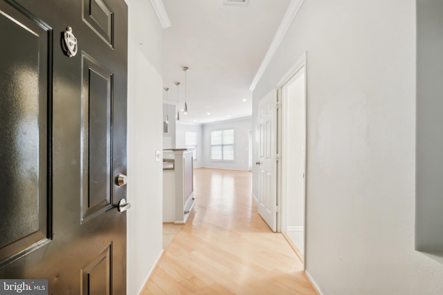 hall featuring ornamental molding and light hardwood / wood-style flooring