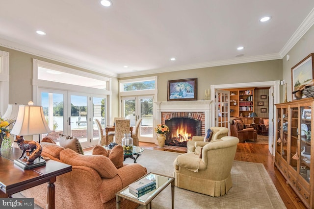 living room featuring hardwood / wood-style floors, a fireplace, crown molding, and french doors