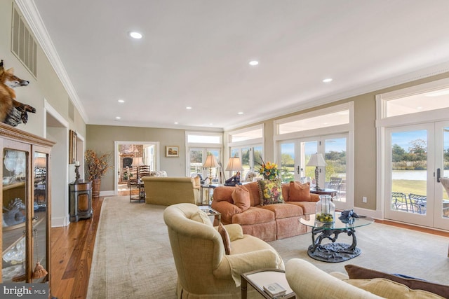 living room with crown molding, french doors, and light wood-type flooring