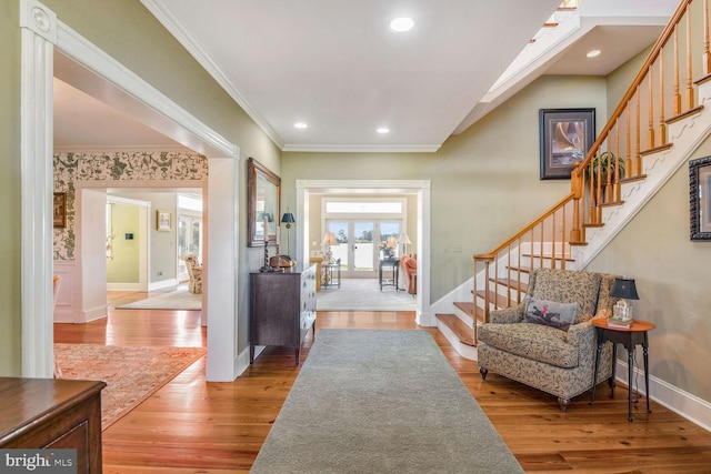 entryway with ornamental molding and light hardwood / wood-style flooring