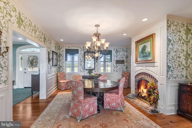 dining room with a brick fireplace, an inviting chandelier, crown molding, and dark wood-type flooring