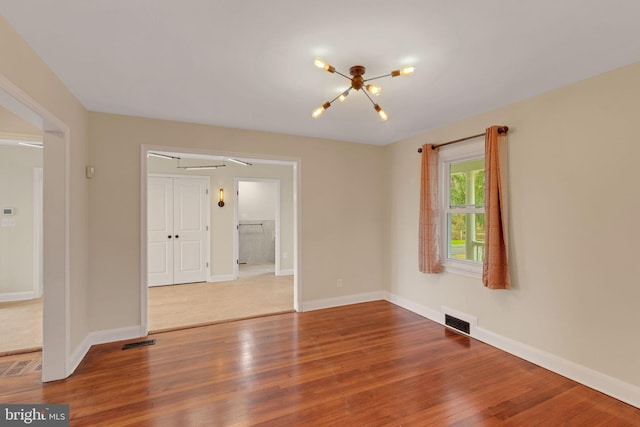 unfurnished room featuring wood-type flooring and a chandelier