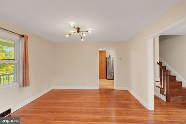 spare room with light hardwood / wood-style flooring and a notable chandelier