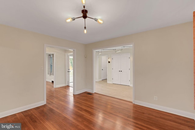 unfurnished room featuring hardwood / wood-style floors and an inviting chandelier