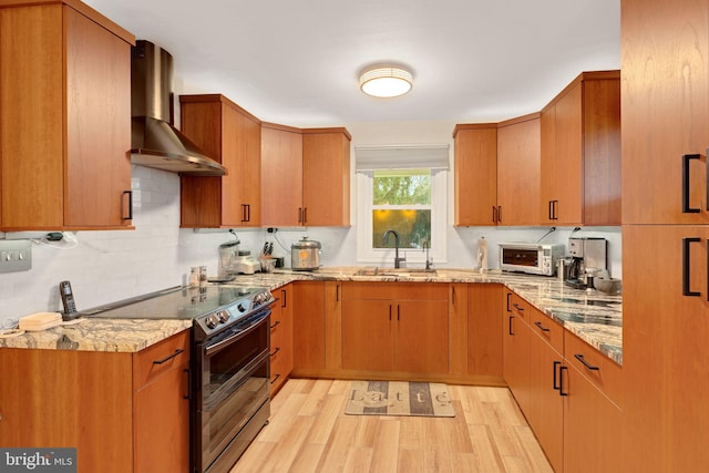 kitchen featuring light stone countertops, sink, wall chimney exhaust hood, black / electric stove, and light wood-type flooring