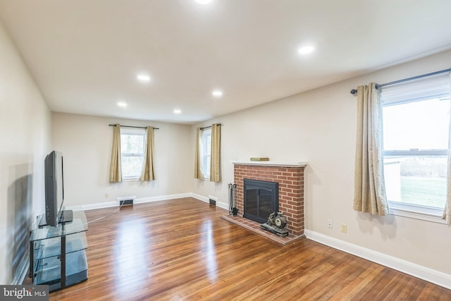 unfurnished living room with dark wood-type flooring and a brick fireplace