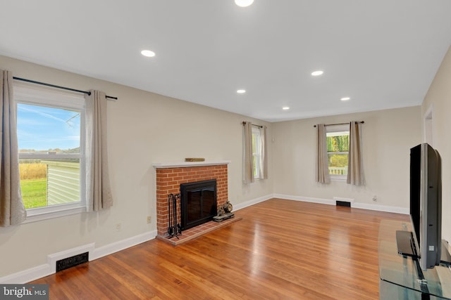 unfurnished living room with light hardwood / wood-style floors and a brick fireplace