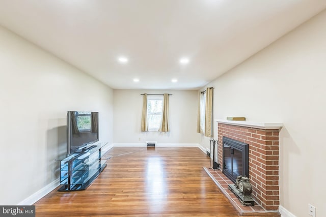 living room featuring wood-type flooring and a brick fireplace