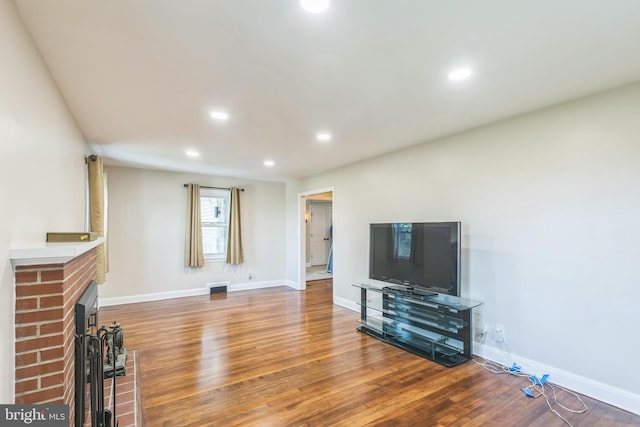 living room with hardwood / wood-style flooring and a brick fireplace