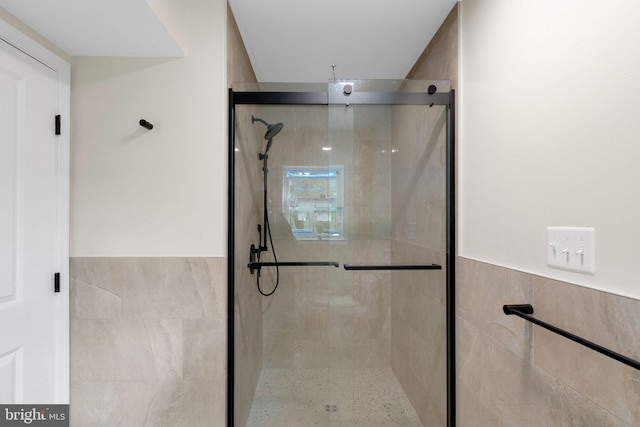 bathroom featuring a shower with shower door and tile walls