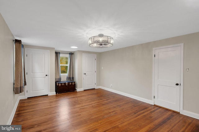 empty room featuring dark hardwood / wood-style flooring and an inviting chandelier