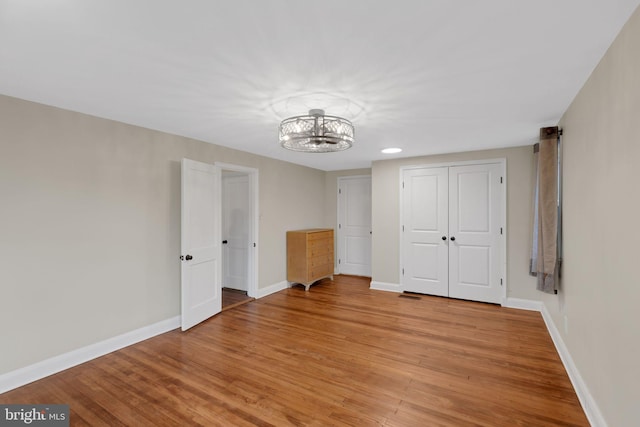 unfurnished bedroom featuring light hardwood / wood-style flooring and an inviting chandelier