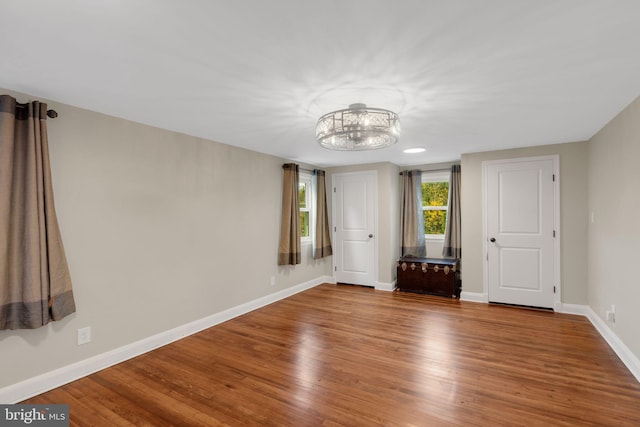 empty room with hardwood / wood-style flooring and an inviting chandelier