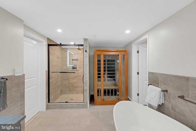 bathroom featuring shower with separate bathtub, tile patterned floors, and tile walls