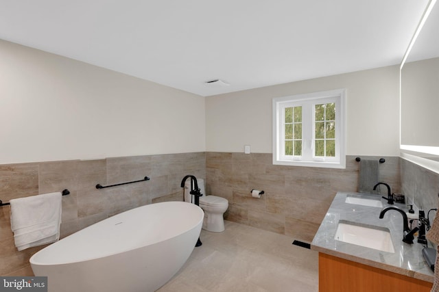 bathroom featuring vanity, toilet, tile walls, and a tub