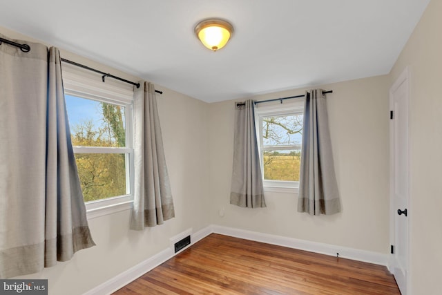 spare room with hardwood / wood-style floors and plenty of natural light