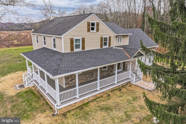 rear view of house featuring covered porch and a lawn