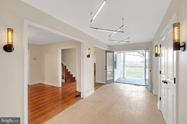 foyer featuring light wood-type flooring, french doors, and an inviting chandelier