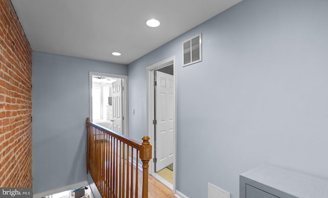 hall featuring brick wall and light hardwood / wood-style floors