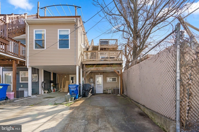 back of house with a carport, a wooden deck, and central AC