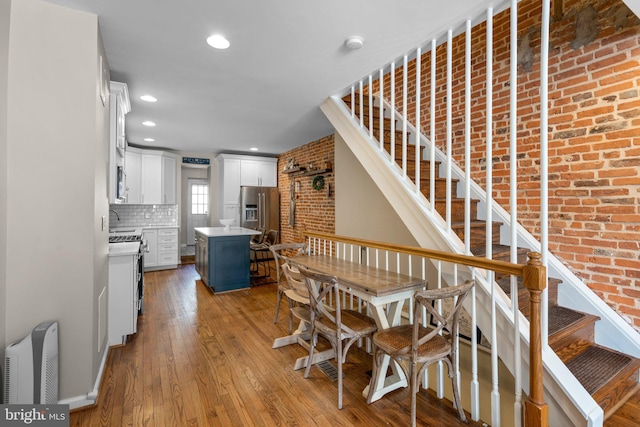 dining area with brick wall, sink, and light hardwood / wood-style flooring