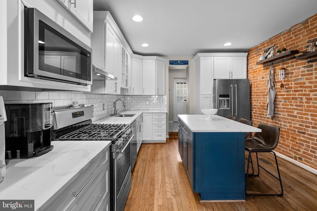 kitchen featuring stainless steel appliances, white cabinets, and a kitchen bar