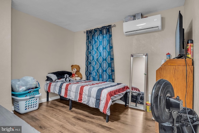 bedroom featuring hardwood / wood-style floors and an AC wall unit