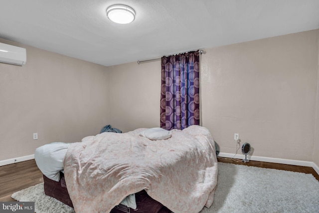 bedroom with an AC wall unit and dark hardwood / wood-style floors