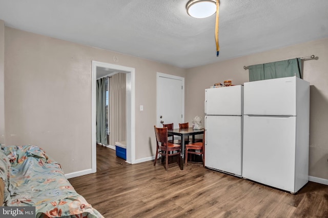 kitchen with white fridge, dark wood-type flooring, and a textured ceiling