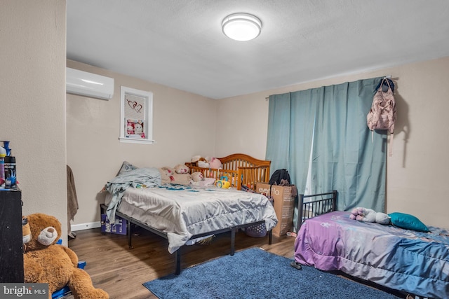 bedroom featuring hardwood / wood-style flooring and a wall unit AC