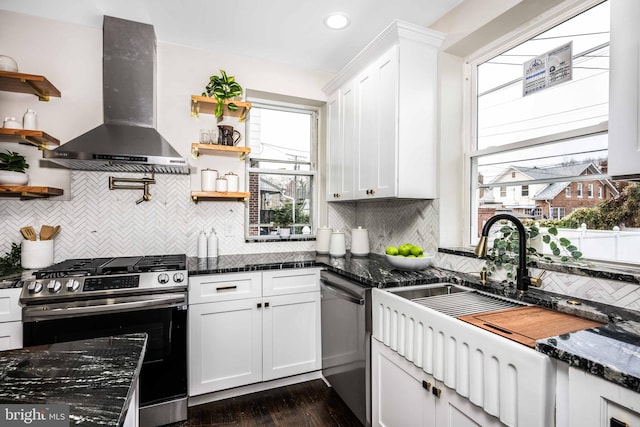 kitchen featuring white cabinets, appliances with stainless steel finishes, dark stone counters, and wall chimney exhaust hood