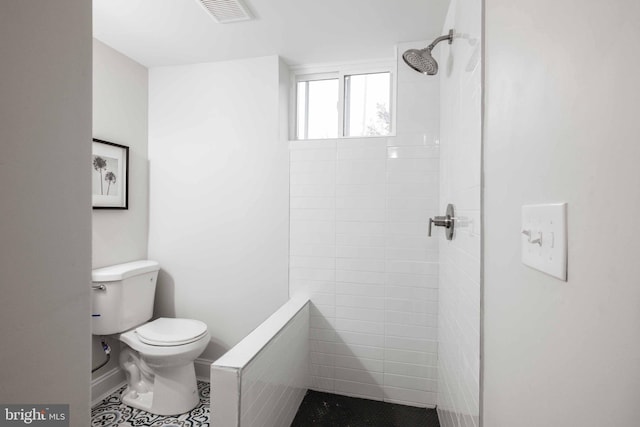 bathroom featuring toilet, tile patterned flooring, and tiled shower