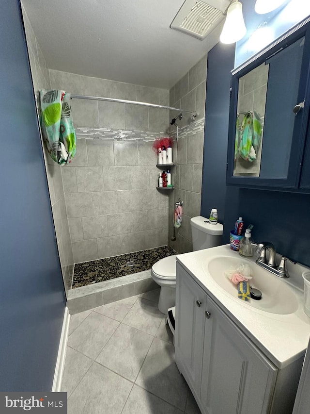 bathroom featuring tile patterned floors, vanity, toilet, and a tile shower