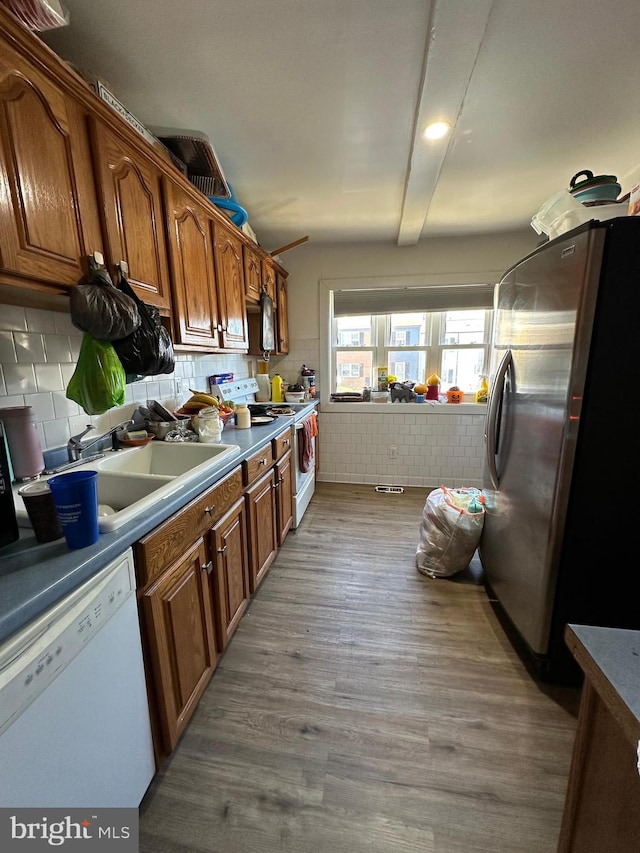 kitchen with decorative backsplash, white appliances, sink, and light hardwood / wood-style flooring