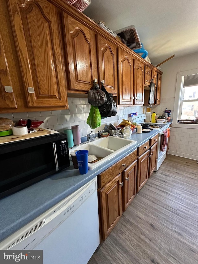 kitchen with tasteful backsplash, light hardwood / wood-style flooring, white appliances, and sink