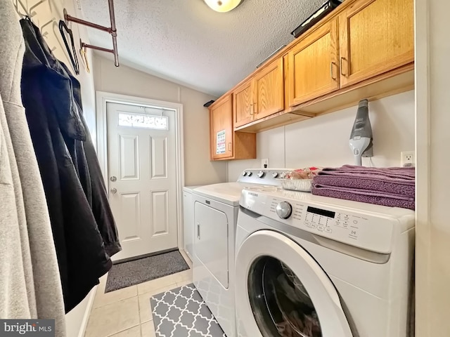 laundry room featuring washer and clothes dryer, cabinets, light tile patterned floors, and a textured ceiling