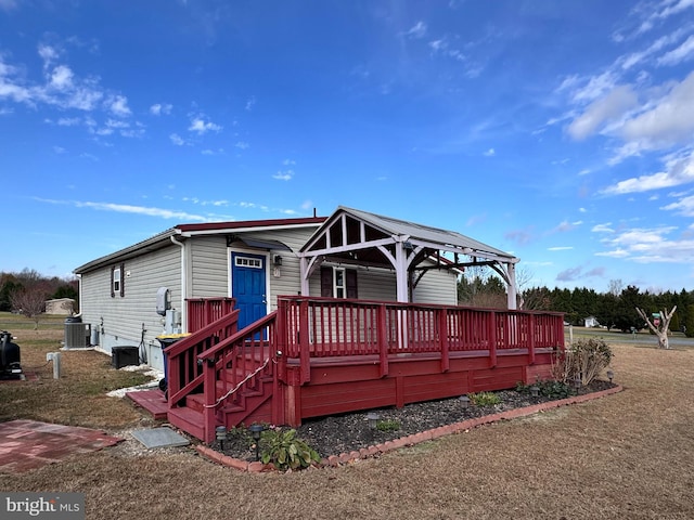 back of property with central AC unit, a deck, and a yard